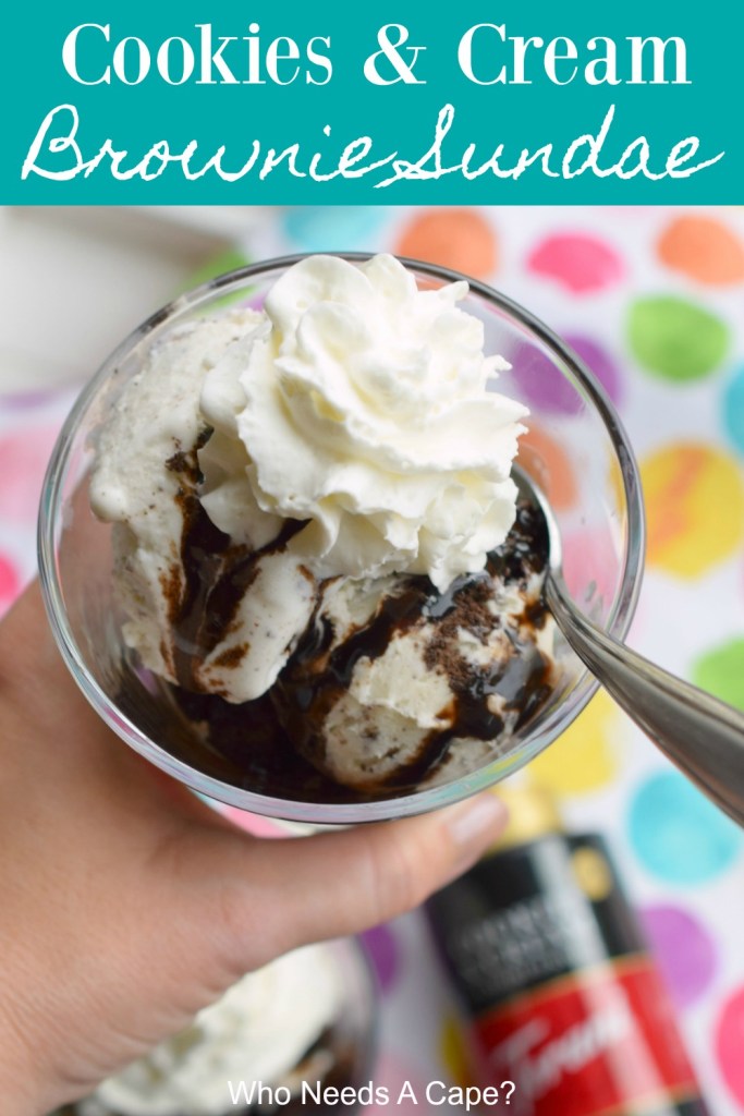 cookies & cream brownie sundae with whipped cream and spoon in glass held over multi colored polka dot fabric