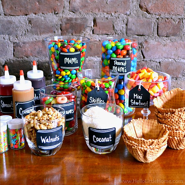Ice Cream Sundae Bar Supplies and Toppings arranged on a wood table.