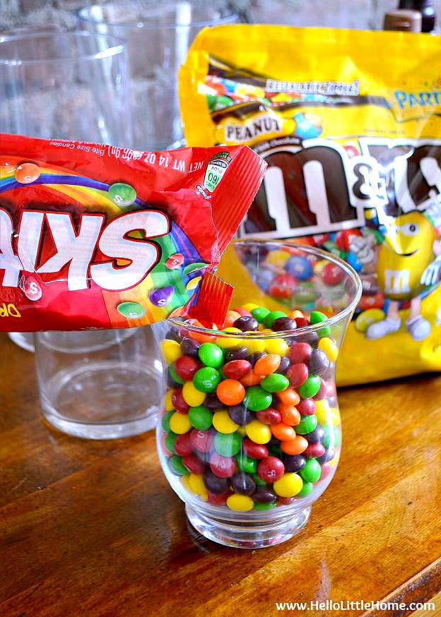 Pouring a bag of candy into a glass container.