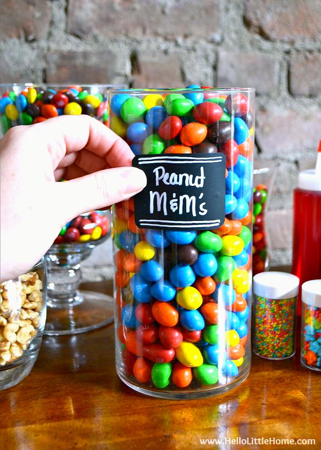 A hand applying a label to a glass jar of candy.