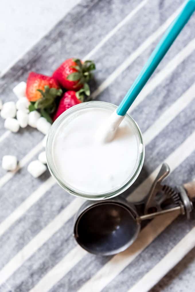 An image of a jar of marshmallow ice cream topping with a spoon in it.