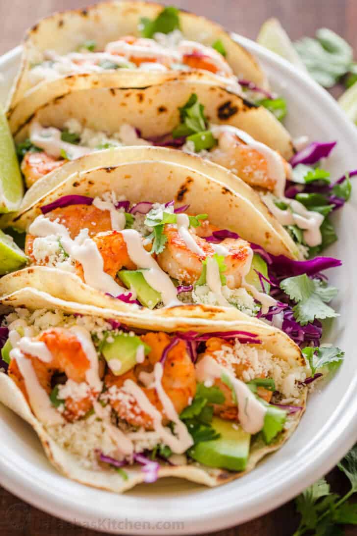 Shrimp tacos on a platter drizzled with shrimp taco sauce