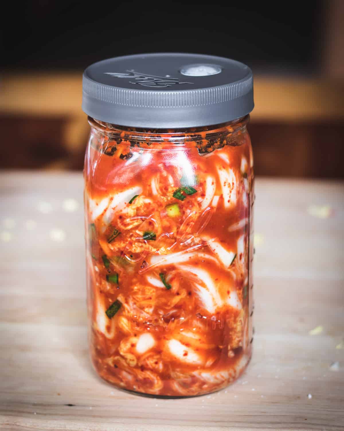 Kimchi is a spicy Korean side dish that is traditionally fermented, similar to sauerkraut. It is usually made with napa cabbage along with other vegetables like carrots, onions, ginger, and garlic. Korean chili flakes give it a spicy kick! Kimchi is surprisingly easy to make and so delicious! a jar of kimchi fermenting