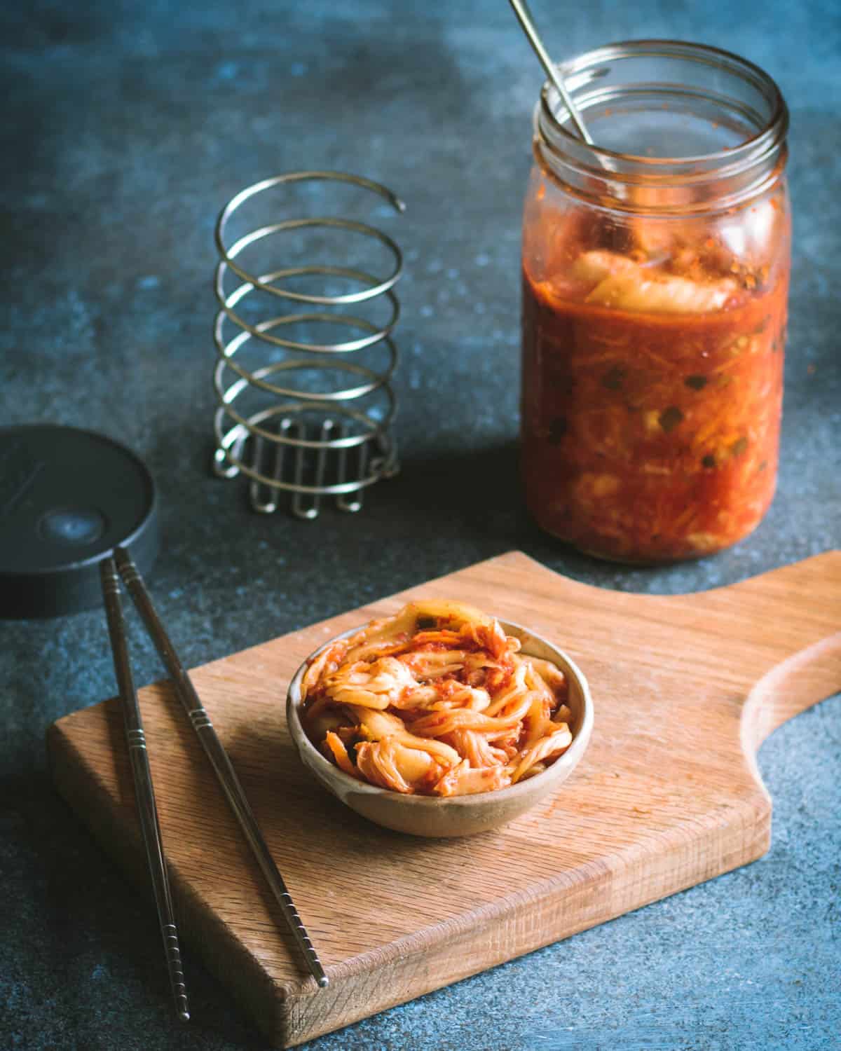 Kimchi is a spicy Korean side dish that is traditionally fermented, similar to sauerkraut. It is usually made with napa cabbage along with other vegetables like carrots, onions, ginger, and garlic. Korean chili flakes give it a spicy kick! Kimchi is surprisingly easy to make and so delicious! finished kimchi in a bowl