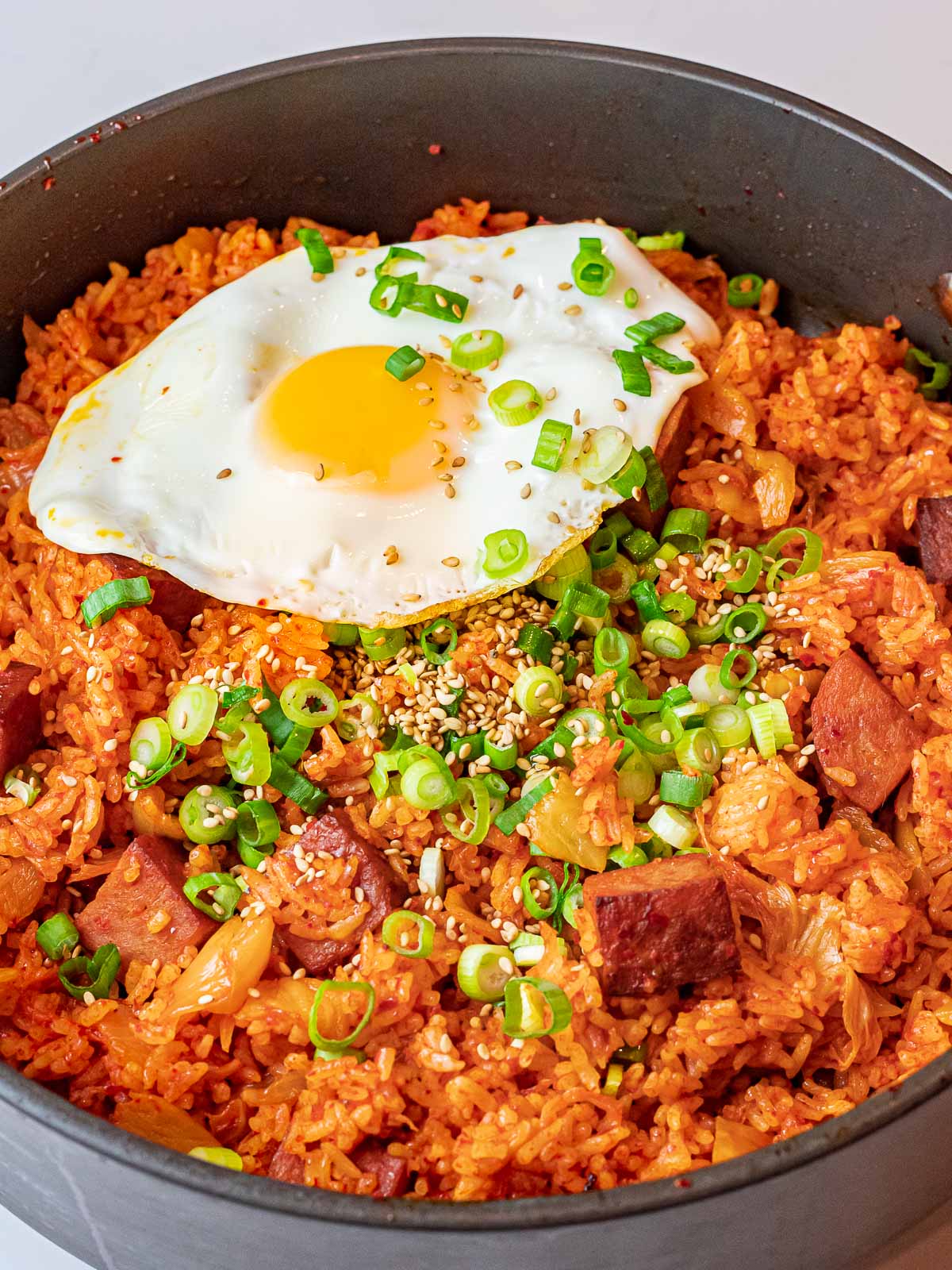 Kimchi Fried Rice with Spam 35 kimchi fried rice with spam and a fried sunny side up egg with scallions in a pan