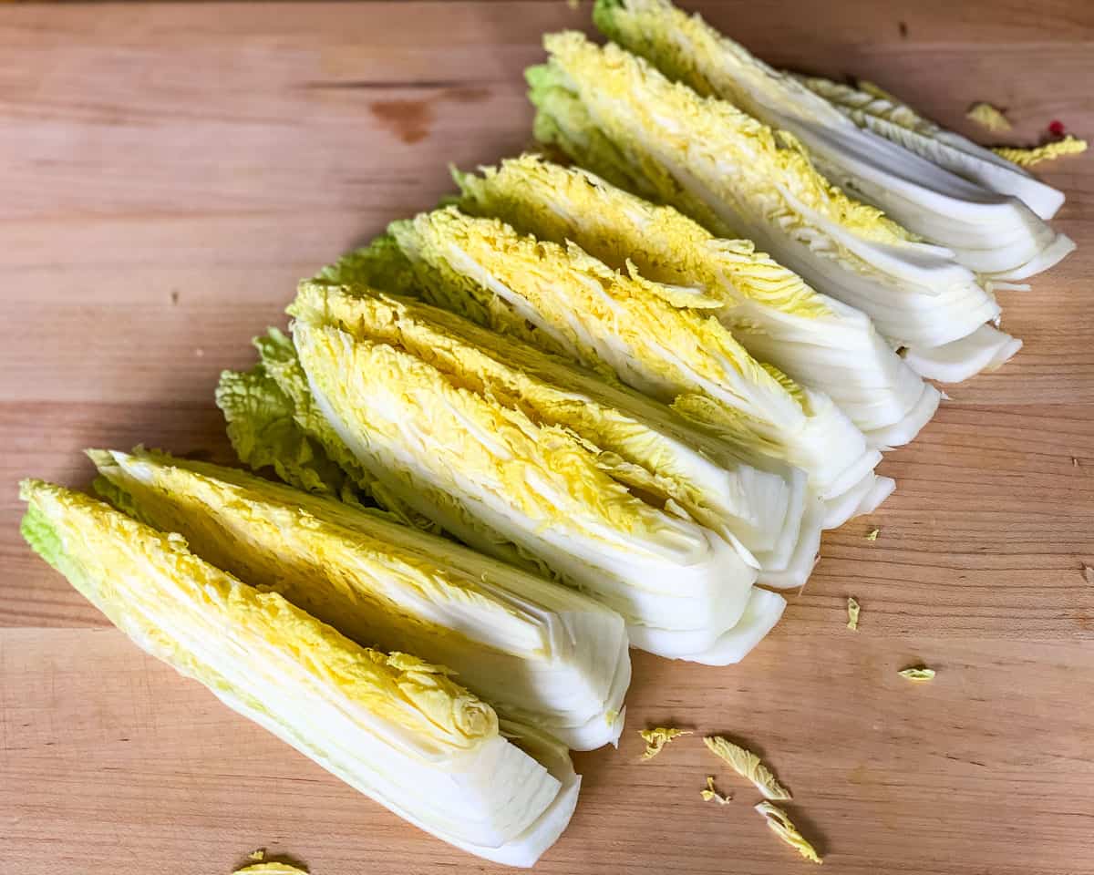 Kimchi is a spicy Korean side dish that is traditionally fermented, similar to sauerkraut. It is usually made with napa cabbage along with other vegetables like carrots, onions, ginger, and garlic. Korean chili flakes give it a spicy kick! Kimchi is surprisingly easy to make and so delicious! napa cabbage cut into long ribbons