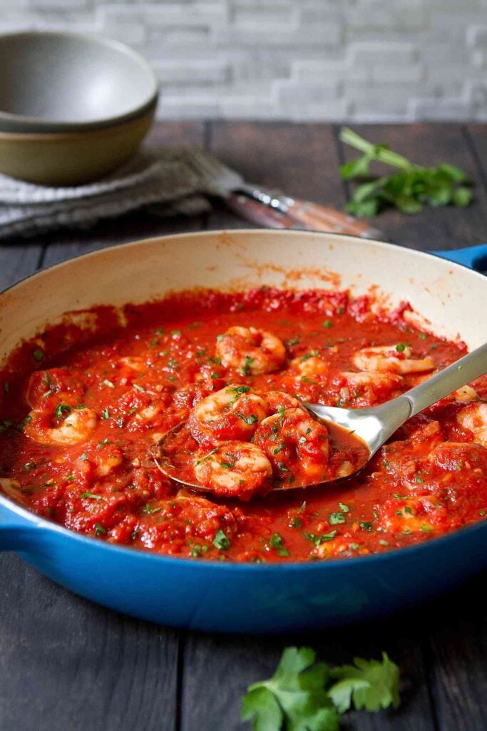 Shrimp in Red Sauce Recipe 18 Seafood tomato sauce in a large blue skillet, on wood table.