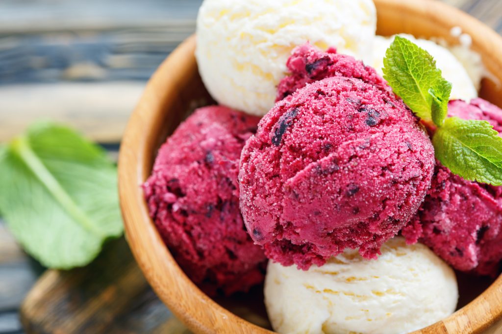 Wooden bowl with homemade lemon and berry ice cream, selective focus.