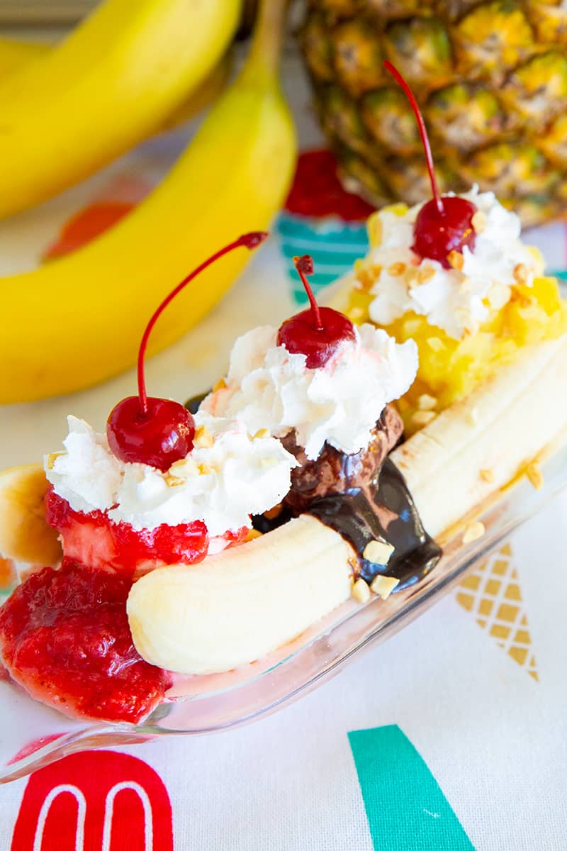 Old-Fashioned Ice Cream Banana Split 12 Ice Cream Banana Split on a banana boat dish, ripe banana and pineapple on background